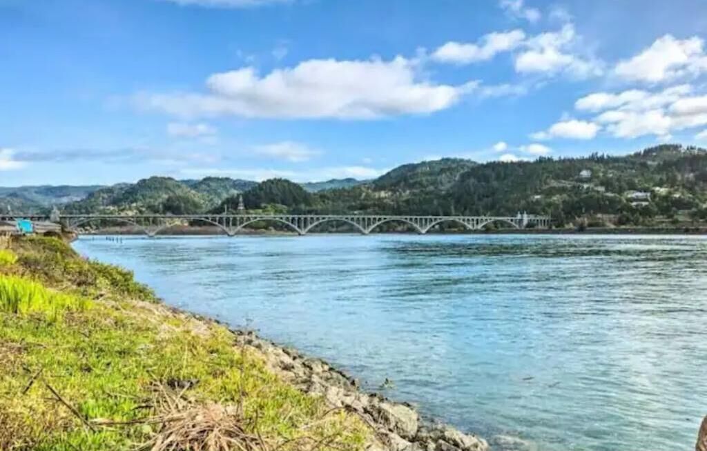 A river with a bridge and hills in the background.