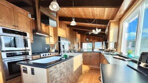 A modern kitchen with wooden cabinets, stainless steel appliances, and a large island.