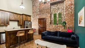 A kitchen with wooden cabinets, a bar area, a dark blue sofa, and a bench. - Hidden Gem – Steps to French Quarter Food & FunHistoric Charm: Walk to Bourbon/French Quarter (Room in a Hotel) (New Orleans)