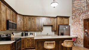 A kitchen with wooden cabinets, a stainless steel refrigerator, a microwave, and a coffee maker. - Hidden Gem – Steps to French Quarter Food & FunHistoric Charm: Walk to Bourbon/French Quarter (Room in a Hotel) (New Orleans)