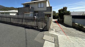 Une maison à deux étages avec un garage, une cour clôturée et un ciel dégagé.