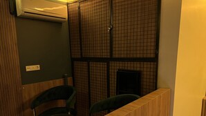 Una stanza piccola e accogliente con una reception in legno, due poltrone verdi, un tavolino rotondo e un televisore nero.