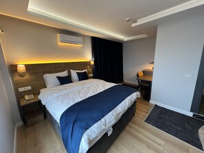 A hotel room with a large bed, bedside tables, a desk, and an air conditioning unit. - The Blue Suites (Istanbul)