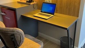 Un'area di lavoro compatta con un portatile, un armadietto rosso e una sedia.