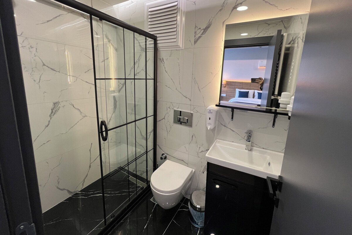 Une salle de bain moderne avec une douche à parois de verre, des toilettes, un lavabo et un miroir.
