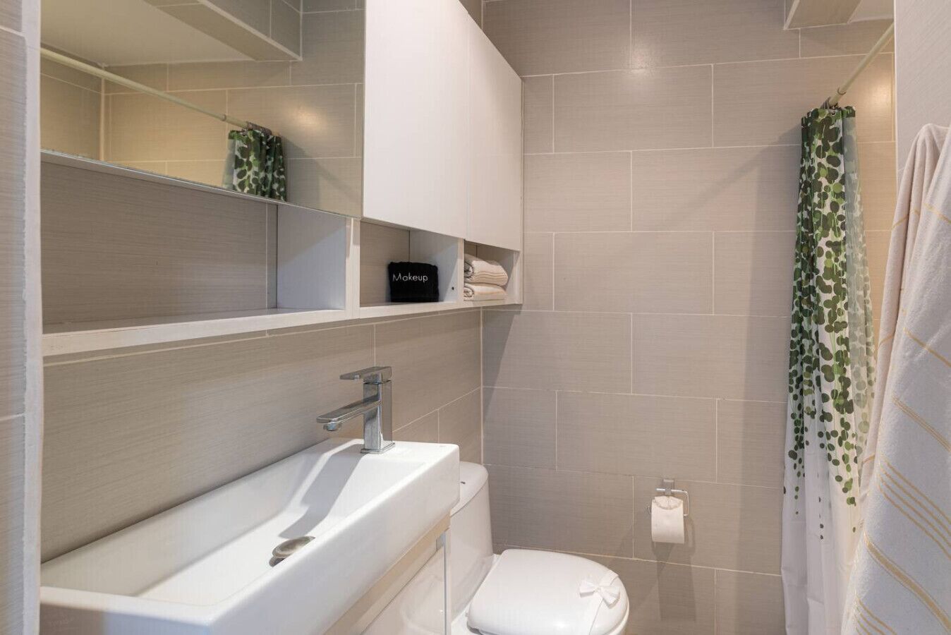 A bathroom with a white sink, a toilet, a mirror, and a shower curtain.
