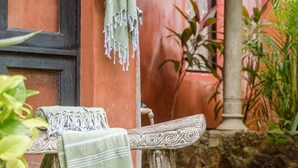 A rustic outdoor seating area with a bench and a table, a hanging towel, and a stone pillar. - Studio across the street from beach, top location (Playa Langosta)