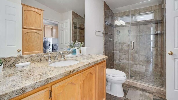 A bathroom with a granite countertop, a white sink, a toilet, and a glass-enclosed shower. - Bodega Bay Oasis  - Wine Tastings Included (Bodega Bay)