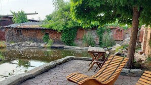 A courtyard with a pond, wooden benches, and a stone pathway.