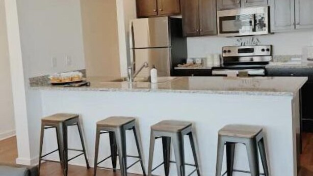 Een moderne keuken met een centraal eiland, barkrukken en roestvrijstalen apparatuur.