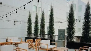 Een terras met houten meubels en lichtslingers.