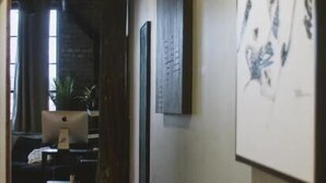 A hallway with a modern interior design, featuring a wooden floor, a hanging light fixture, and a framed artwork on the wall. - Premier Loft Downtown Detroit (Detroit)