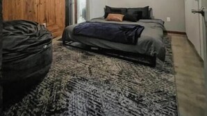 A narrow room with a bed, a wooden door, and a large rug. - Premier Loft Downtown Detroit (Detroit)