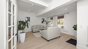 A spacious living room with a sofa, a coffee table, and a potted plant. - 2BR Home in Menlo Park Near Stanford University! (Menlo Park)
