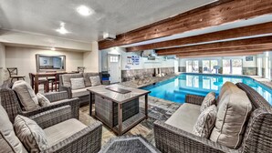 Zona junto a la piscina con mobiliario de mimbre, una piscina y un televisor.