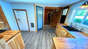 A modern kitchen with wooden cabinetry, a built-in stove, and a large window providing natural light.
