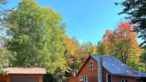 A two-story log cabin with a metal roof, a garage, and a stone chimney.