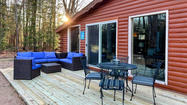 A log cabin with a deck, a blue sofa, and a table with chairs.