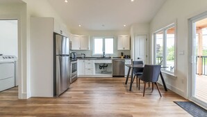 Een moderne keuken met witte kasten, roestvrijstalen apparatuur en een eethoek met een tafel en stoelen.