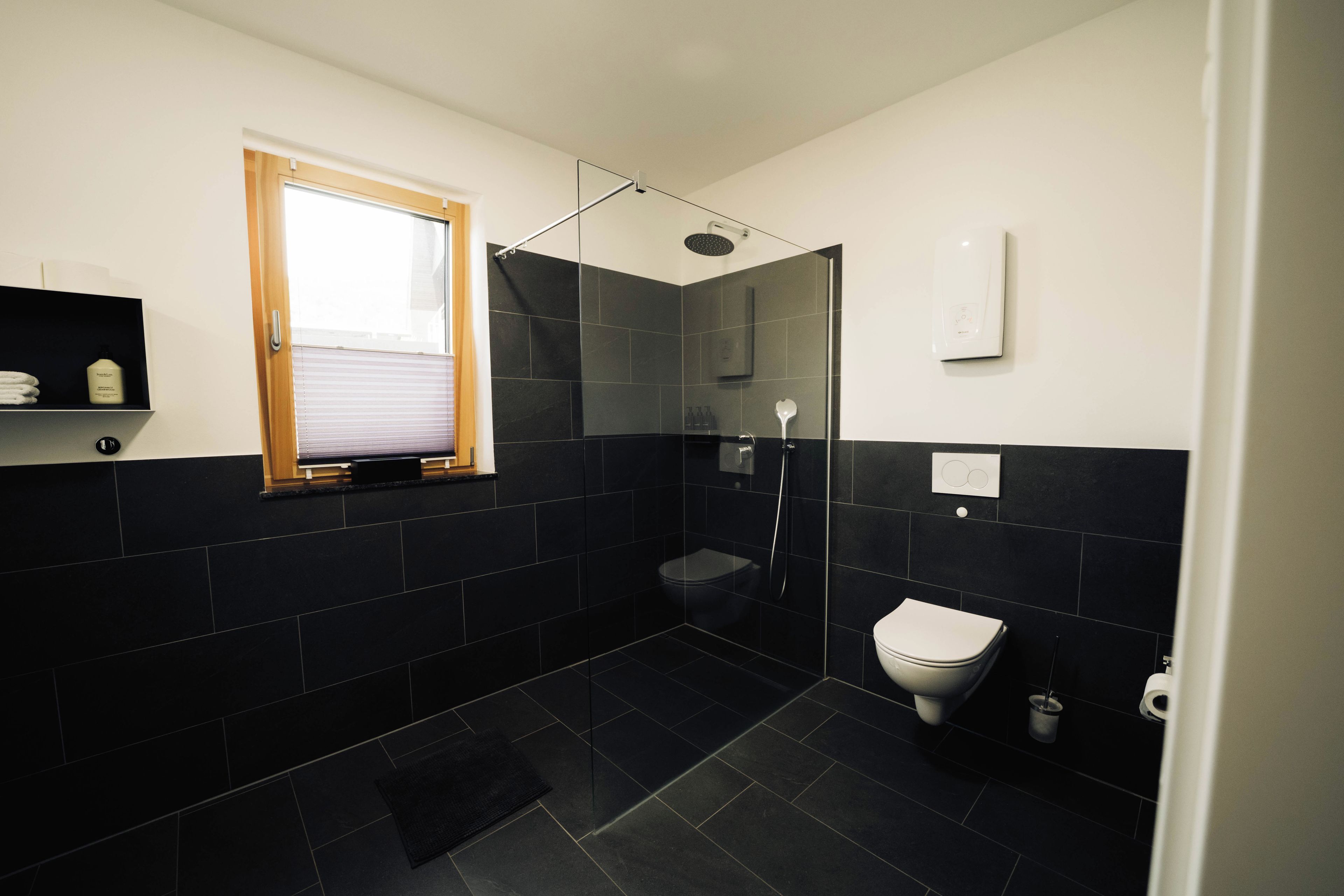 Un baño moderno con ducha, inodoro y ventana.