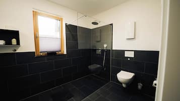 Un baño moderno con ducha, inodoro y ventana.