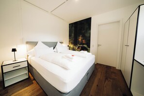 Un dormitorio moderno con una cama grande, una mesita de noche, una lámpara y una puerta.