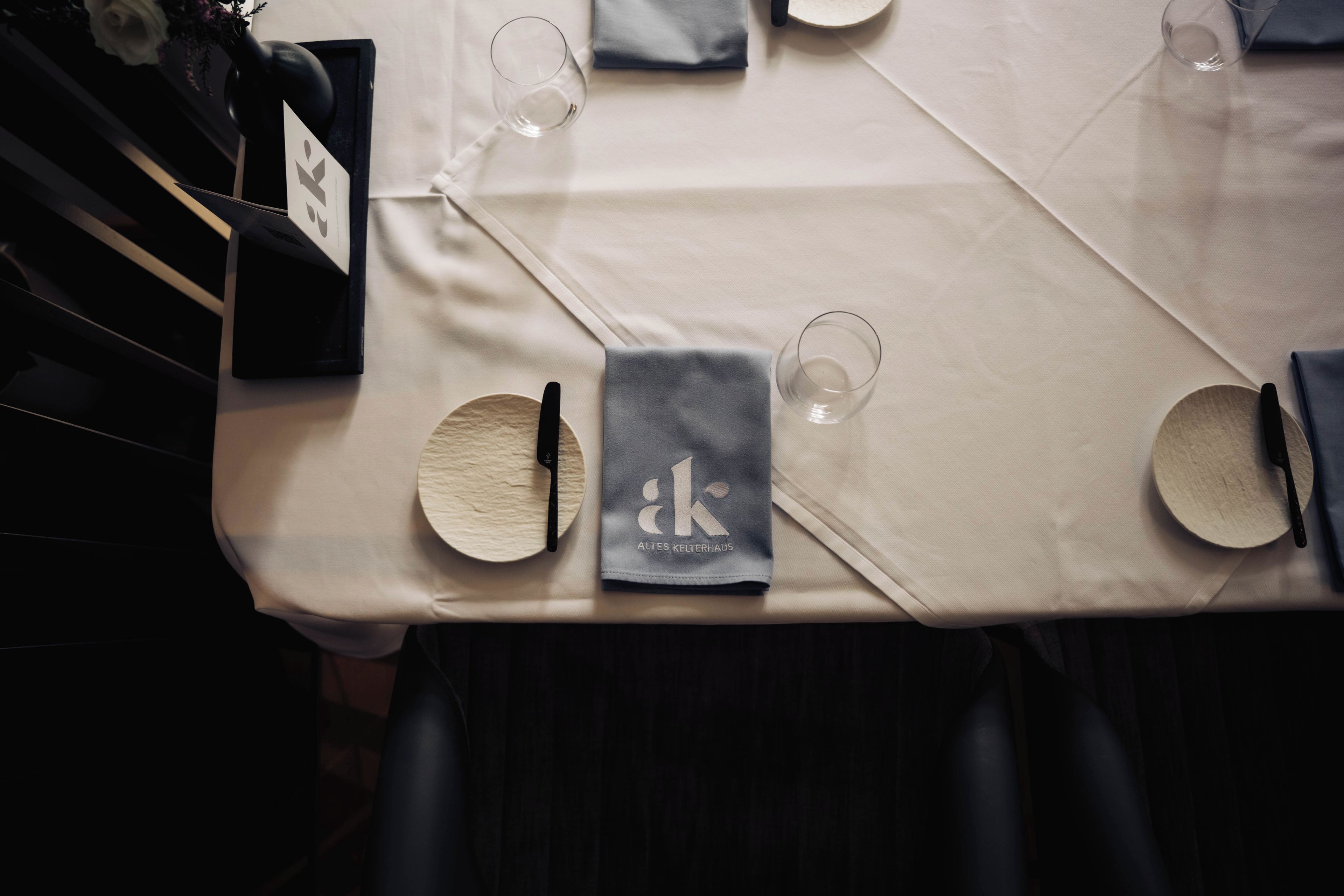 Une table dressée avec une serviette, des couverts et des verres, ce qui indique qu’elle est prête pour le repas.