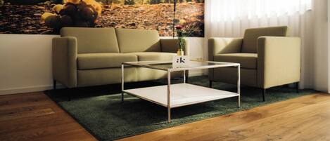 A modern living room with a sofa, a coffee table, and a large landscape painting on the wall.