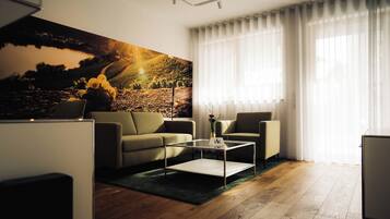 Una sala de estar moderna con un sofá, sillones, una mesa de centro y un cuadro grande.
