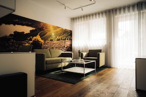 Una sala de estar moderna con un sofá, sillones, una mesa de centro y un cuadro grande.