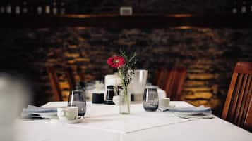 Una mesa puesta con un jarrón de flores, vasos y cubiertos.