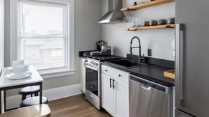 A modern kitchen with a stove, oven, and refrigerator, wooden flooring, and a window with blinds. - Hotel Quality/ Walkable / Free Parking/ Office #11 (Lakewood)