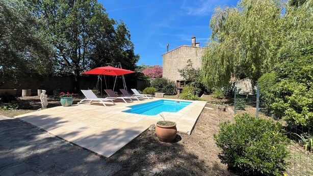 A rectangular pool with lounge chairs and a red umbrella. - Les Glycines (Trausse)