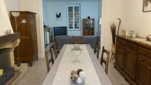 A dining area with a long table, chairs, a fireplace, a television, and a bookshelf. - Les Glycines (Trausse)