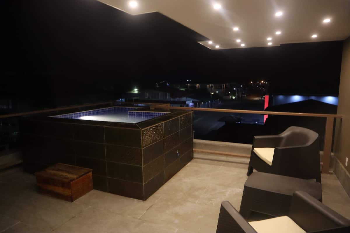 A rooftop terrace with a hot tub, seating area, and a view of the city at night.