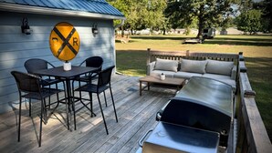 Eine Terrasse mit Tisch und Stühlen, einem Grill und einer Sitzecke.