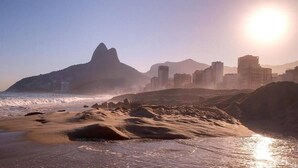 A beach with waves, a mountain, and buildings in the background. - Studio Bartho Leblon (Leblon Rio de Janeiro)
