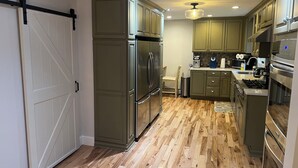 A kitchen with wooden flooring, stainless steel appliances, and green cabinetry. - Chautauqua Lake Front Property - Short Walk to the Village of Bemus Point! (Bemus Point)