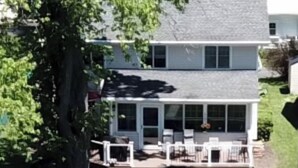 A two-story house with a covered patio and a dock extending into a body of water. - Chautauqua Lake Front Property - Short Walk to the Village of Bemus Point! (Bemus Point)