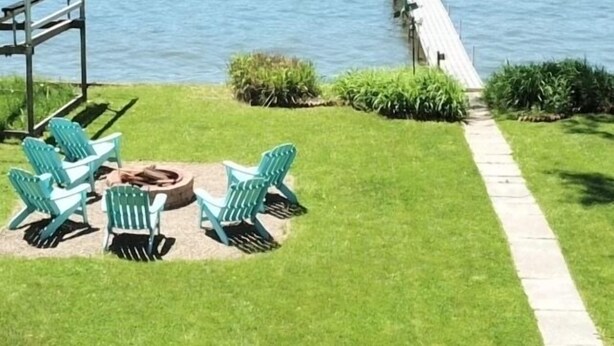A grassy area with a dock extending into a body of water, a bridge in the background, and a gazebo with chairs. - Chautauqua Lake Front Property - Short Walk to the Village of Bemus Point! (Bemus Point)