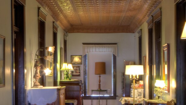 A hallway with wooden flooring, a Christmas tree, and various furniture including a desk, chairs, and lamps.