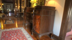 A hallway with wooden flooring, a red patterned rug, and a dark wooden dresser with multiple drawers.