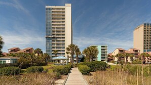 A modern hotel with a central glass tower, a covered walkway, and surrounding greenery. - Whoa!  Amazing view!! (Myrtle Beach)