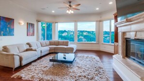 A spacious living room with a large sectional sofa, a glass coffee table, and a fireplace.