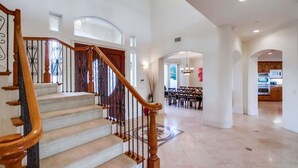 A spacious interior with a grand staircase, a dining area, and a kitchen.