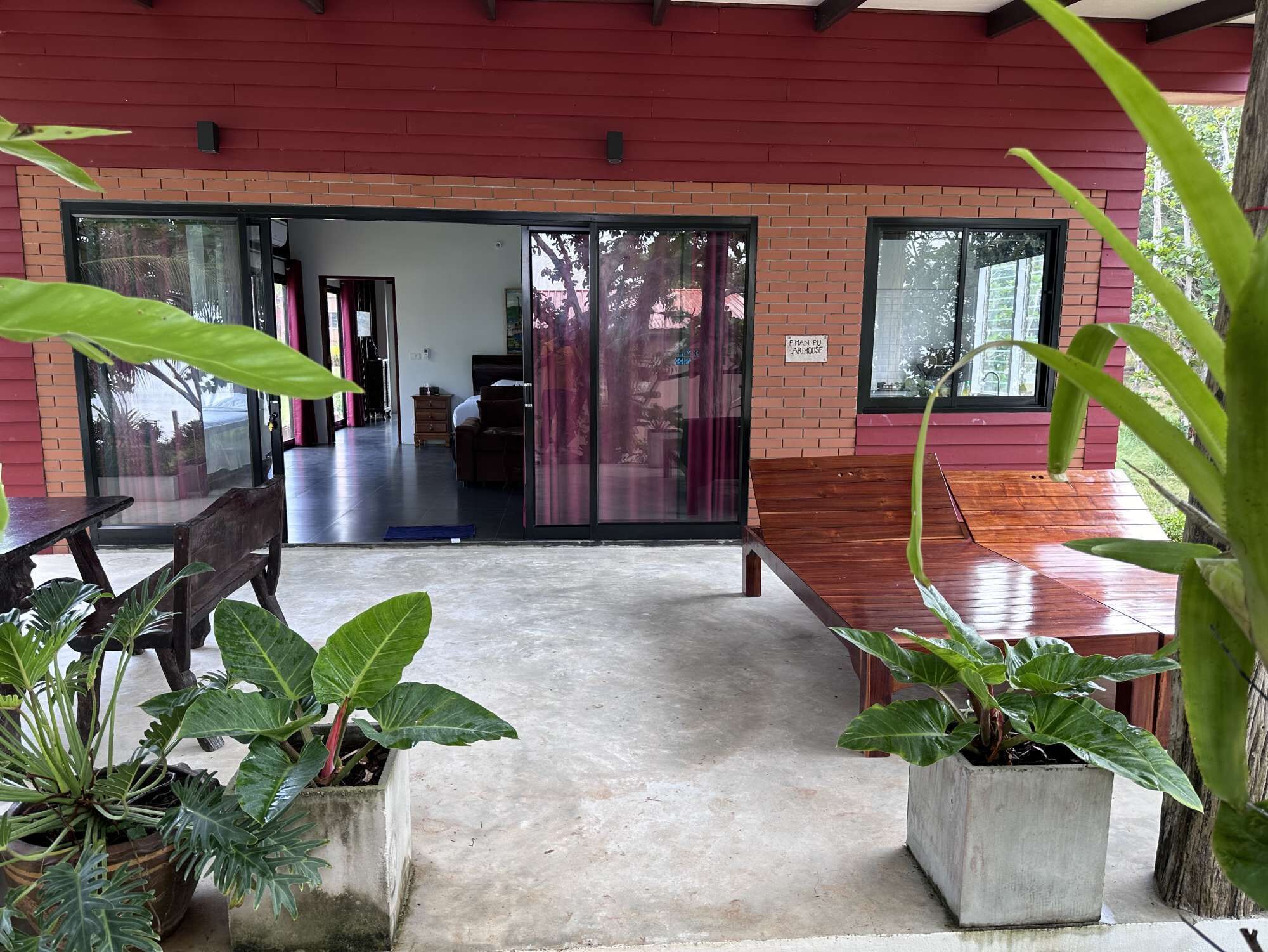 An open-plan area with a concrete floor, wooden furniture, and potted plants.