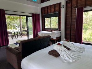Ein Hotelzimmer mit Bett, einer Couch, einem Tisch und einem Fenster mit Vorhängen.