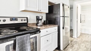 A kitchen with white cabinets, a black refrigerator, a coffee maker, and a stove. - Private Tacoma Retreat Near Lakes & Puget Sound! (Lakewood)