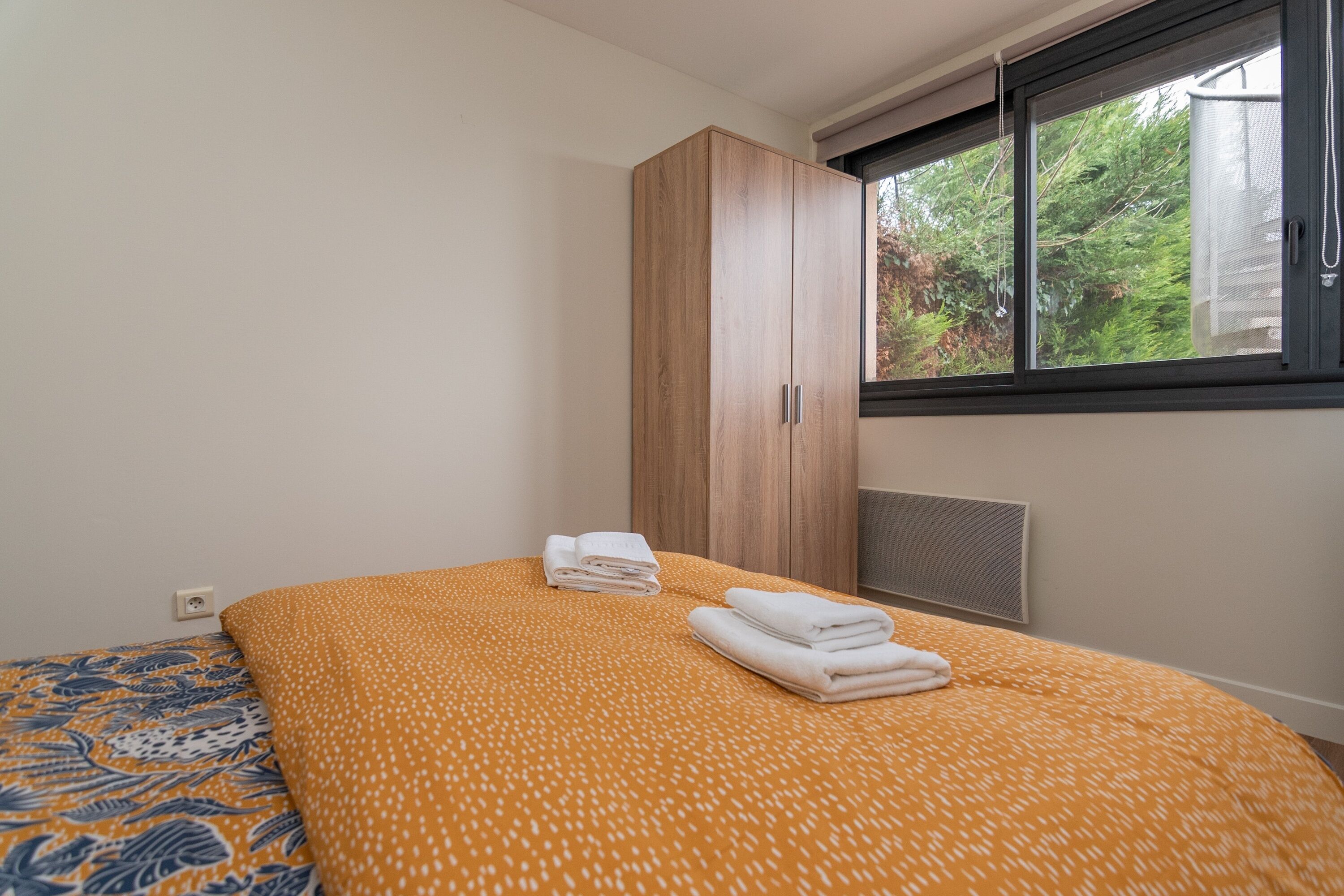 Une chambre à coucher comprenant un lit, une armoire et une fenêtre donnant sur un paysage verdoyant.