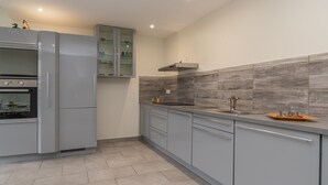 A modern kitchen with grey cabinets, a built-in oven, and a tiled backsplash.